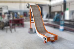 An incline magnetic conveyor system in a factory setting, designed to efficiently transfer sharp steel items and materials between manufacturing cells.