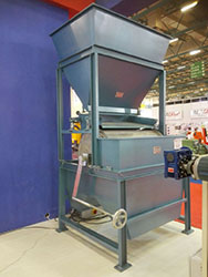 Industrial magnetic drum separator system with a feeding hopper and support frame.