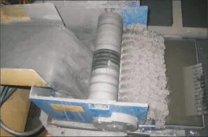 Rotating magnetic roller collecting metallic contaminants from circulating liquid.