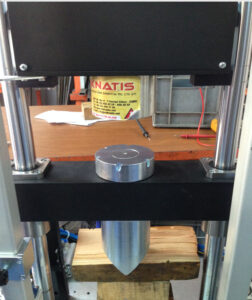 Electro magnet holding a metal component in a vertical industrial test stand.