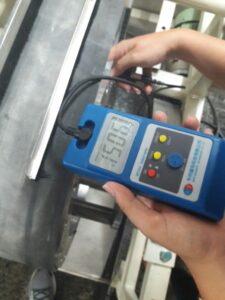 Measuring high-intensity magnetic field strength on a roll separator using a digital Gauss meter.